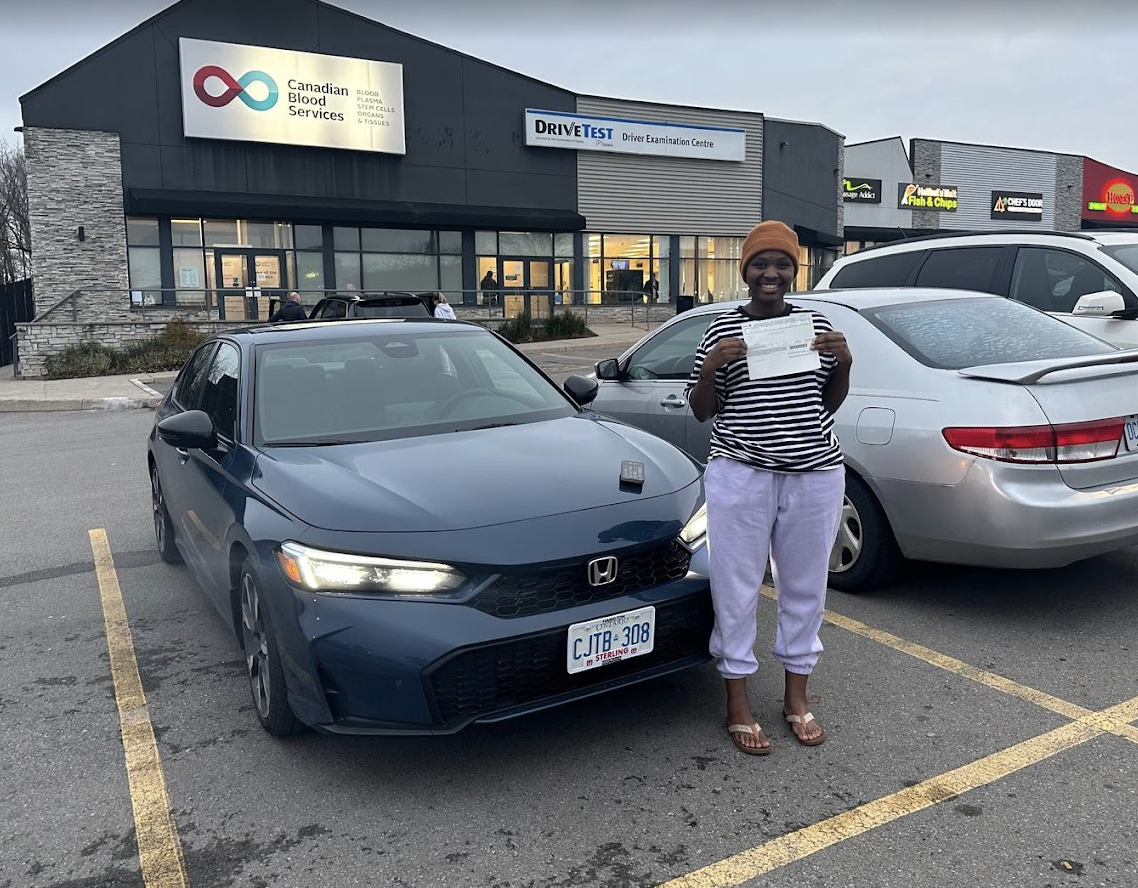 Hamilton SteerWise graduate proudly holding full G license beside instructor car